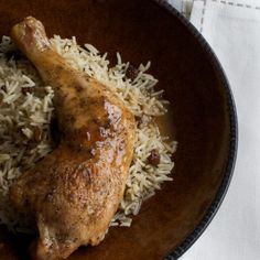 chicken and rice in a brown bowl on top of a white table cloth with a fork