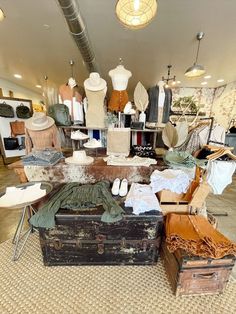 an old trunk is sitting on the floor in front of several pieces of clothing and other items