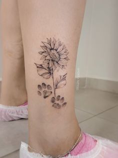 a woman's foot with a sunflower and paw prints on the side of her leg