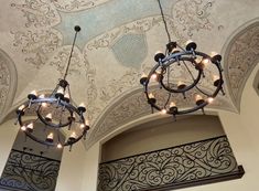 two chandeliers are hanging from the ceiling