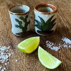 two mugs with lime slices on a wooden table