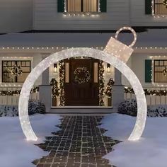 a house is decorated for christmas with white lights and decorations on the front door, along with a lighted arch