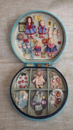 an open blue case with many small dolls in it on a white tableclothed surface