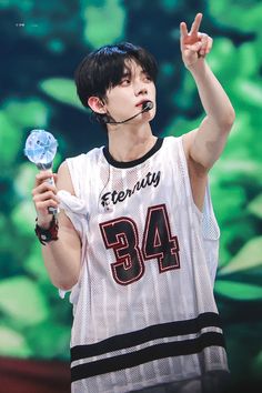 a young man in a white shirt holding up a blue lollipop and making the peace sign