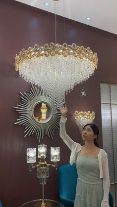 a woman standing in front of a chandelier with many lights hanging from it