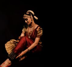 a woman sitting on the ground in a red and gold outfit