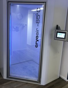 an empty room with a glass door and blue light on the wall, in front of a computer monitor