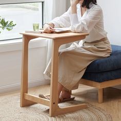 a woman sitting at a desk with her hand on her chin and looking out the window