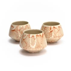 three small cups with designs on them sitting next to each other in front of a white background