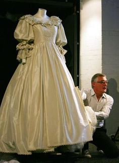 a man kneeling down next to a dress on display