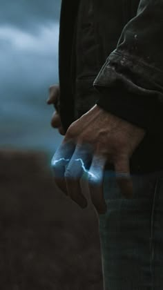 a man is holding his hand out to light up the dark sky with lightning in it