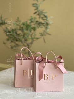 two pink bags with bows on them sitting on a table