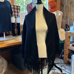 a mannequin wearing a black jacket with fringes on it's shoulders