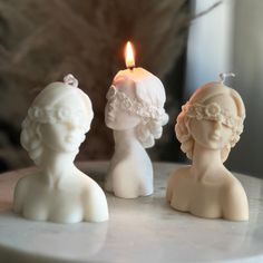 three small white candles sitting next to each other on top of a table with a candle in the middle