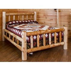 a log bed frame in a bedroom with wooden walls and flooring, along with a quilt on it