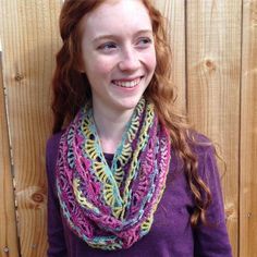 a woman with red hair wearing a multicolored crocheted scarf and smiling