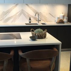 two brown chairs sitting in front of a white counter top next to a kitchen sink