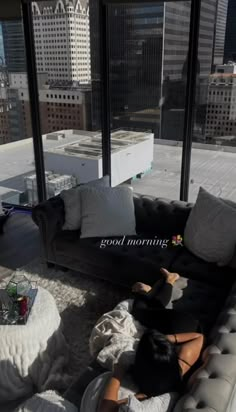 a woman laying on top of a couch in a living room next to a window