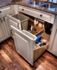 an open cabinet in the middle of a kitchen with wooden floors and white cupboards