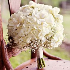 a bouquet of white flowers sitting on top of a wooden chair