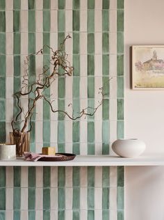 a shelf with vases and other items on top of it in front of a striped wall