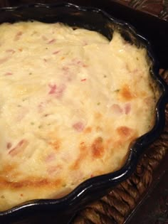 a casserole dish with ham and cheese in a black pan on a wooden table