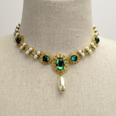 Milady Pauline Necklace in Antique Gold, Pearls & Emerald Green Gems A drop of color can go a long way when you want to stand out of the crowd. With its sophisticated style and colorful gems, the vibrant yet elegant Milady Pauline necklace adds the best of both worlds to your Victorian or Renaissance wedding attire. This stunning Renaissance-inspired pearl necklace features double strands of incandescent chained pearls capped in antique gold between stations of emerald green gems mounted in Emerald Green Necklace Set, Gold And Green Necklace, Gold And Emerald Necklace, Necklace Reference, Emerald Necklace Gold, Double Strand Pearl Necklace, Victorian Necklace, Historical Jewellery, Neck Accessories