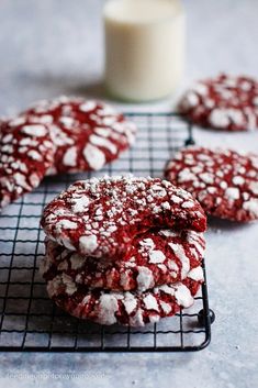 red velvet cookies with powdered sugar on a cooling rack next to a glass of milk