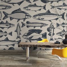 a dining room with fish wallpaper and yellow chairs