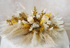 an arrangement of flowers and feathers on a white cloth covered tablecloth in front of a wall