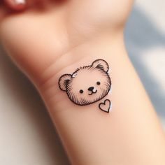 a small tattoo on the wrist of a person with a teddy bear head and heart