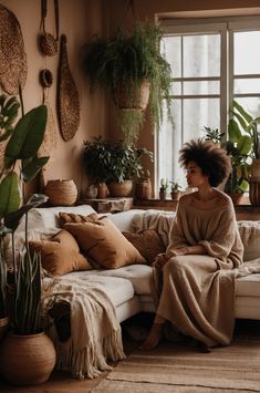 a woman sitting on top of a couch next to potted plants