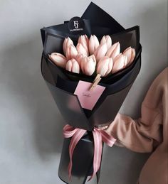 a bouquet of pink tulips wrapped in black paper