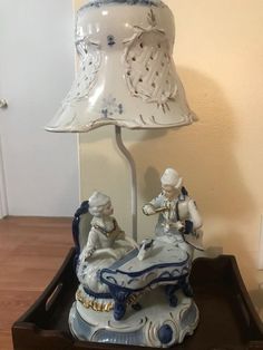 a lamp that is sitting on top of a wooden table with a figurine next to it