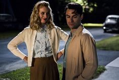 a man and woman standing next to each other in front of a house at night