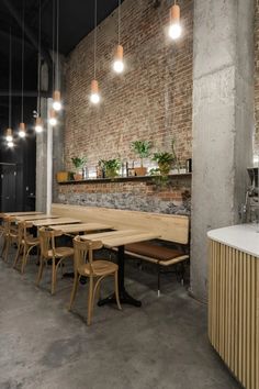 an empty restaurant with tables and chairs in front of a brick wall that has potted plants on it