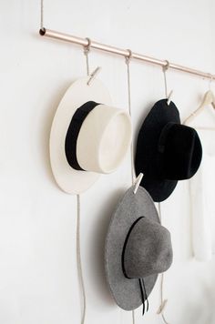 three hats hanging from hooks on a wall