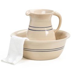 a cream colored pitcher and bowl with a cloth on the side