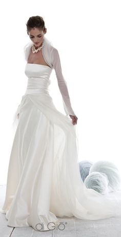 a woman in a white wedding dress standing on the floor with her hand on her hip