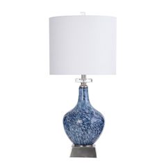 a blue glass lamp with a white shade on the base and a silver metal base