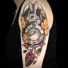 a woman's arm with a rabbit and clock tattoo on it