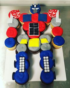 a cake made to look like a robot with cupcakes around it on a table