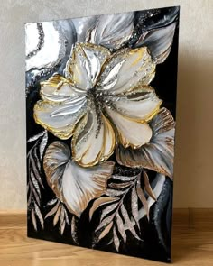 a black and white flower with gold accents on it's side, sitting on a wooden table