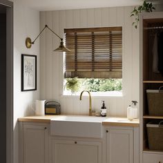 a kitchen with white cabinets and wooden blinds