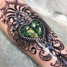 an artistic tattoo design with a green diamond on the left arm and purple flowers in the center