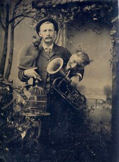 an old black and white photo of a man with two birds on his shoulder holding a trumpet