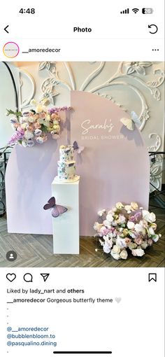 the wedding cake is on display in front of a backdrop with flowers and butterfly decorations