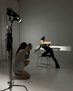 two women sitting on chairs in front of a camera set up for a photo shoot