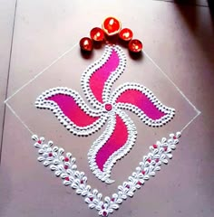 an artistic design on the ground for diwaling with beads and red balls to decorate it