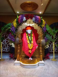 there is a statue of a person sitting on a throne in the middle of flowers